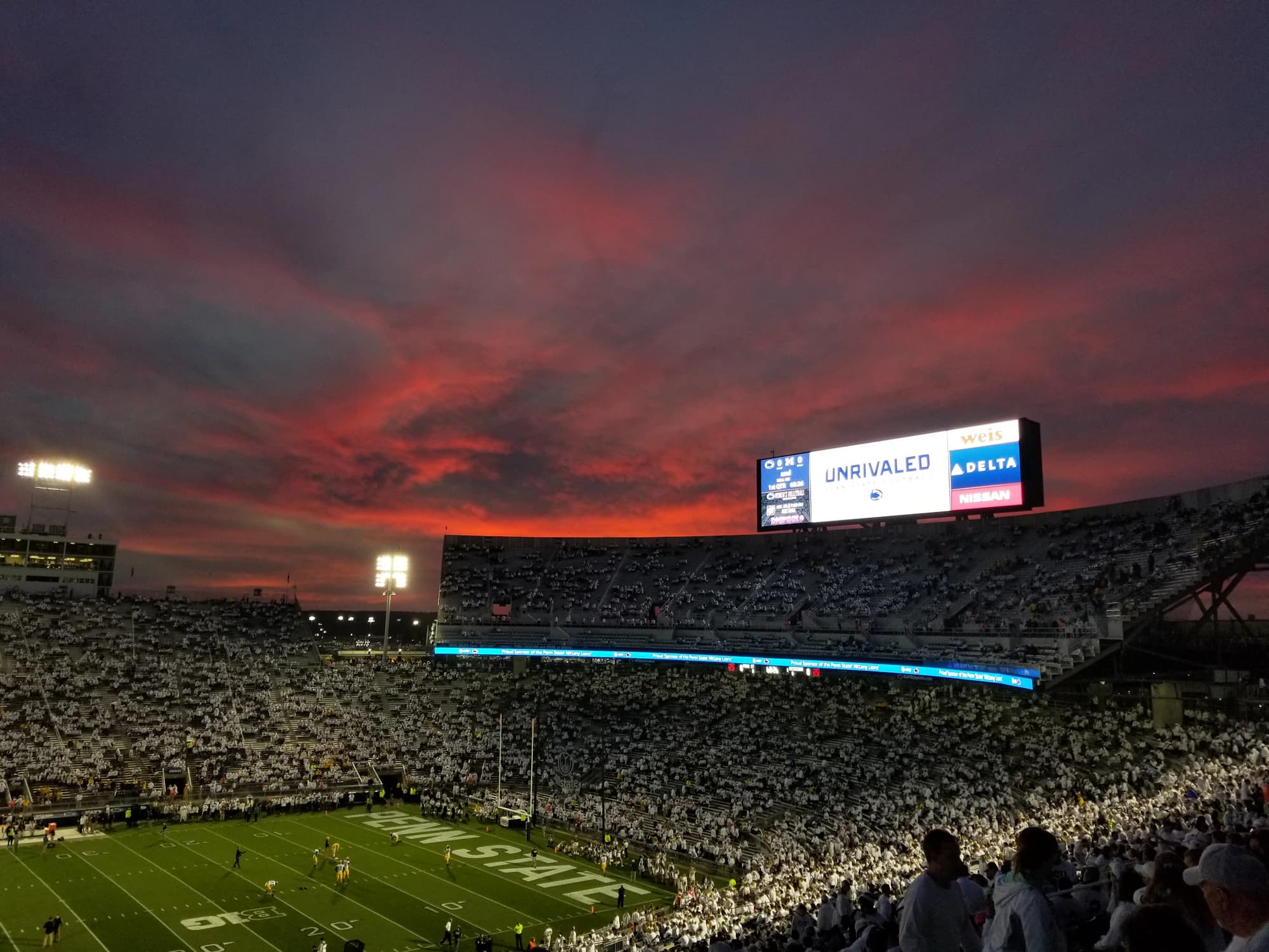 A full Beaver Stadium under a pink sunset sky.