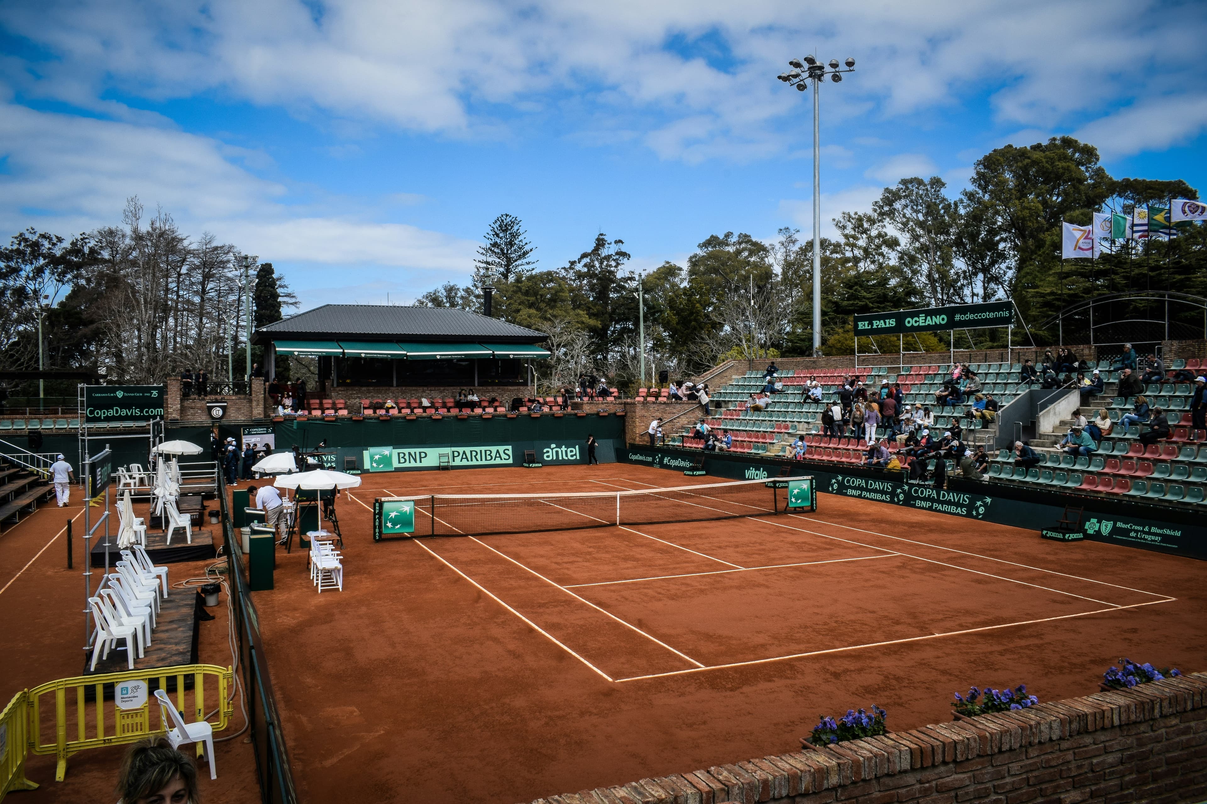 Spectators around a clay tennis court on matchday
